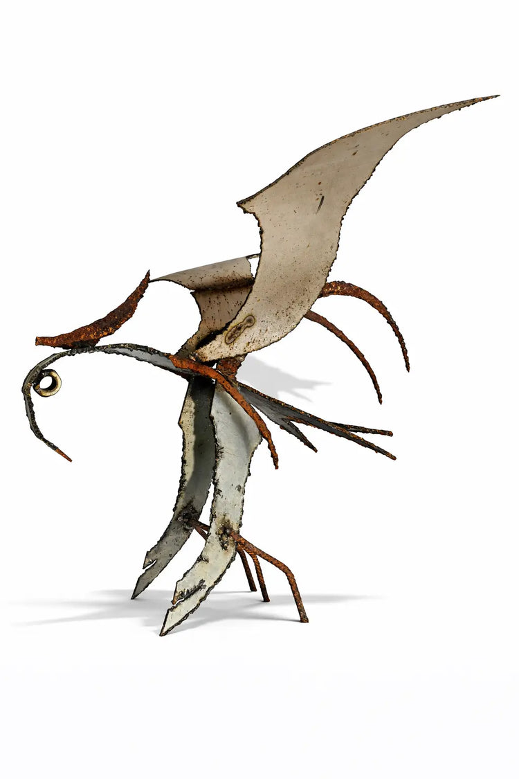 Ses ailes déployées évoquent l’instant fragile de l’envol. Son corps, marqué par la rouille et les textures du temps, révèle la beauté imparfaite du monde brut. Chaque détail est intentionnel, chaque trace raconte une transformation